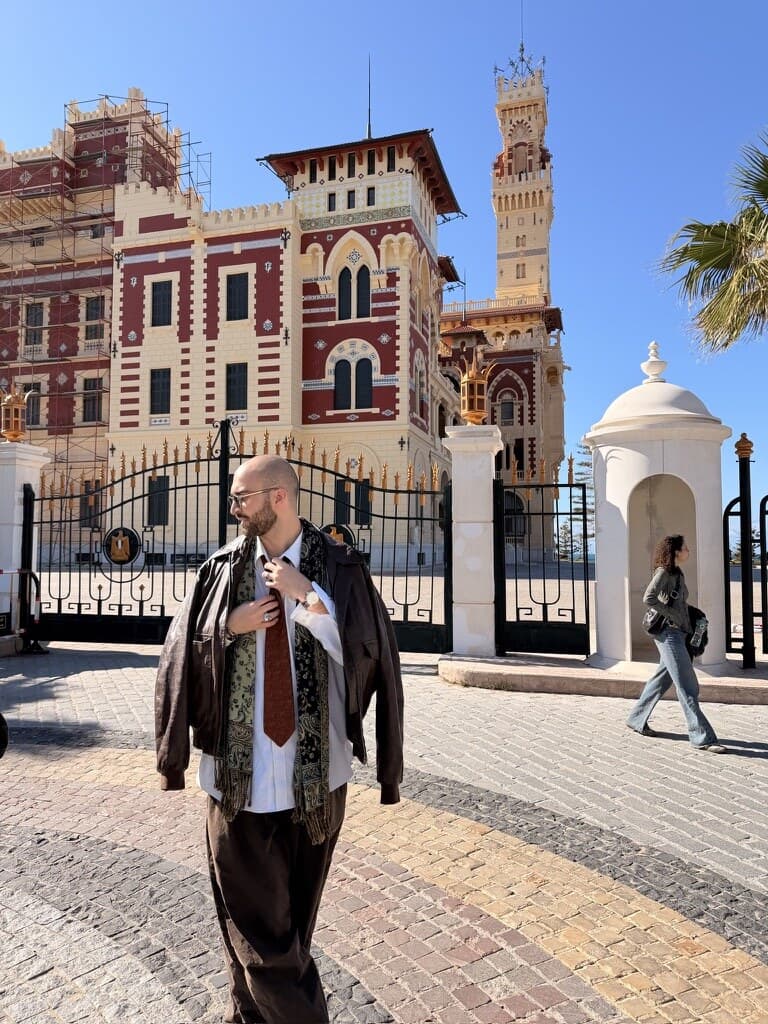 Arthur walking in front of a sunlit historic building