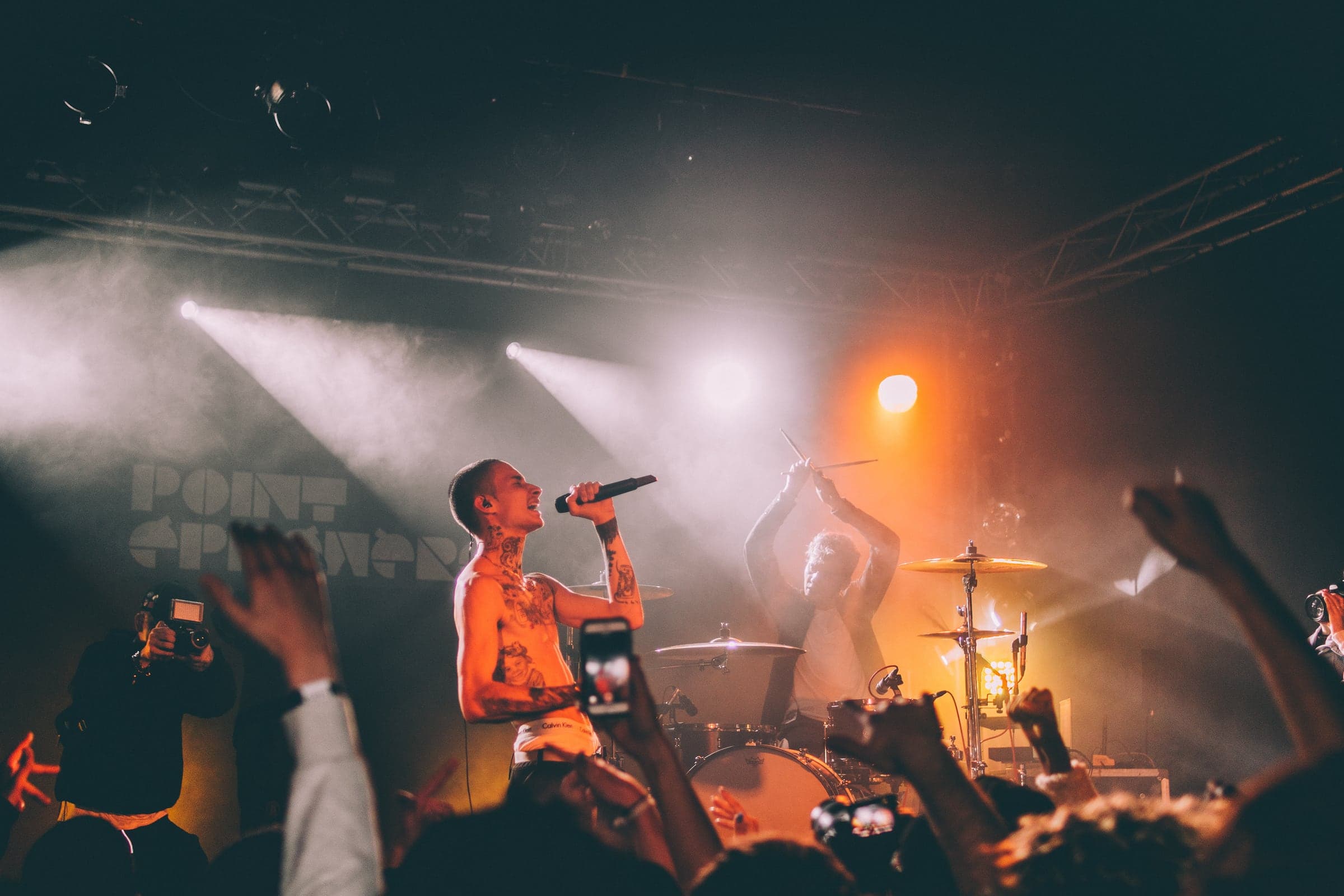 A vocalist performing in warm stage light above a crowd
